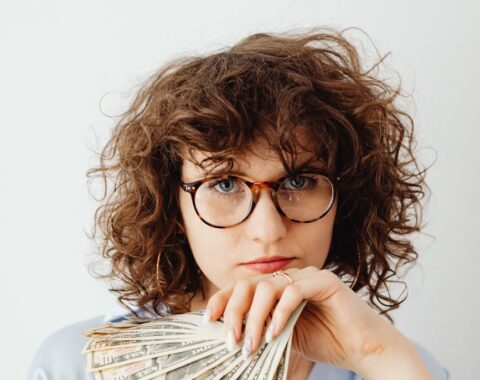 curly haired woman holding paper money